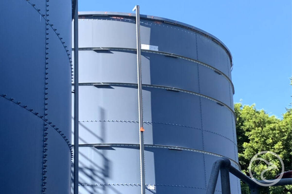 Servicing Industrial & Commercial Water - Large tanks with metal frames against a blue sky.